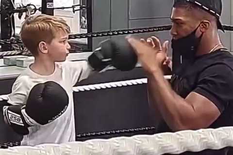 Watch Anthony Joshua teach boy how to box and playfully go down after punch as he takes break from..