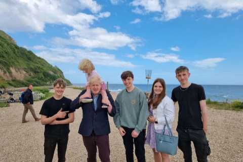 Boris Johnson carries son Wilfred, 4, on his shoulders as they pose with locals during seaside..