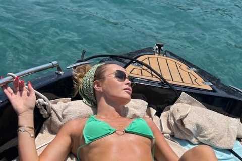 Amanda Holden shows off her incredible figure as she undoes her green bikini on a boat