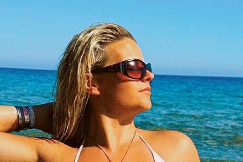 Busty ring girl Apollonia Llewellyn almost slips out of tiny bikini as she tops up her tan on the..